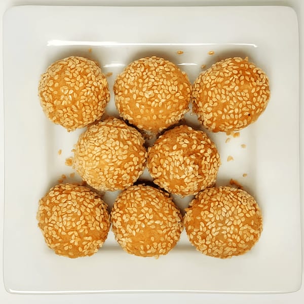 Nine golden-brown sesame balls, a Chinese dessert, arranged on a white square plate.