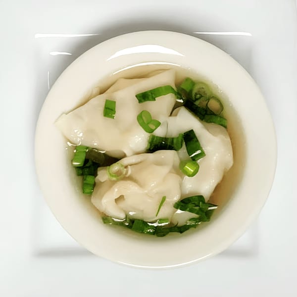 A white bowl of Double Happy wonton soup with green onions on a white background.