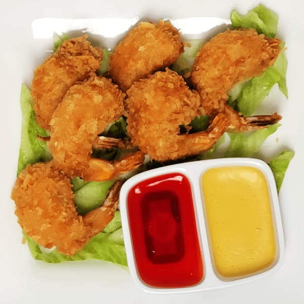 Crispy fried shrimp on a bed of lettuce with red and yellow dipping sauces.